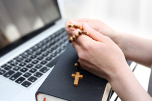 Online religious studies with rosary, bible, and laptop