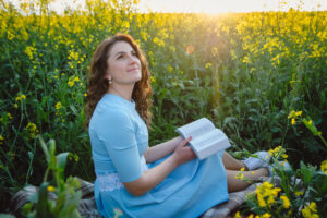 Christian girl reading bible along in sunny field