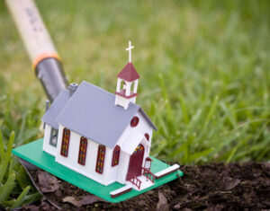 Church planter using shovel on model size church
