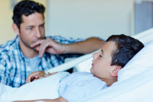 Father with sick son in hospital bed