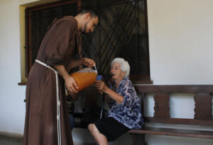 Franciscan friar giving a drink to one in need