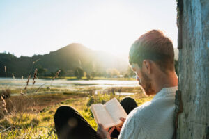 Man reading bible near river's edge
