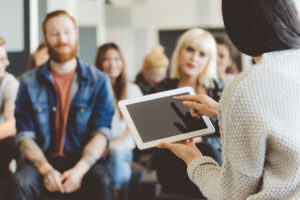 Teaching group of students while holding tablet