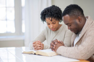 Young couple praying at table