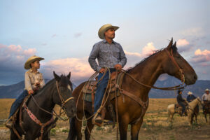 Father and son on horseback in prairie 