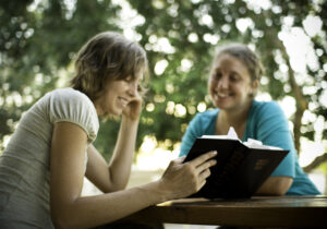 Friends reading bible together outside
