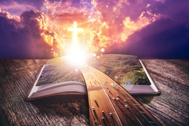 an open bible with light coming out and a highway coming towards the viewer