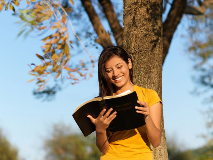 cheerful woman reading bible outside