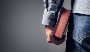 man holding a bible at his side