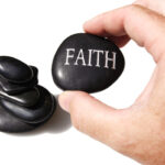 a rock with faith written on it and a hand holding it