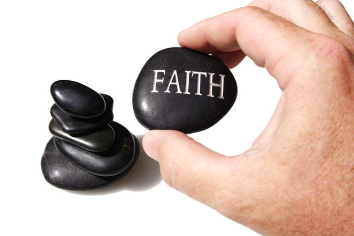 a rock with faith written on it and a hand holding it