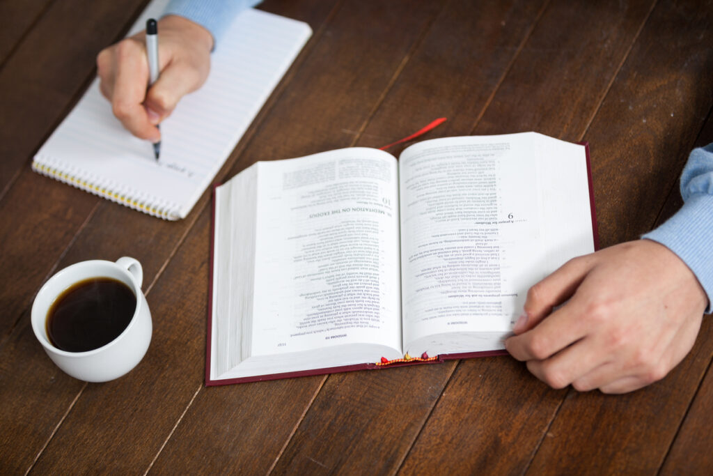 Male ministry coach reading a bible while writing down notes, showing life as a ministry coach.